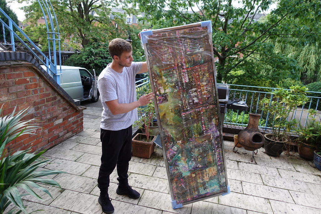 Max carrying a large painting down outdoor steps for delivery