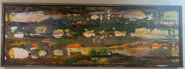 A long horizontal painting in a black frame above a corridor