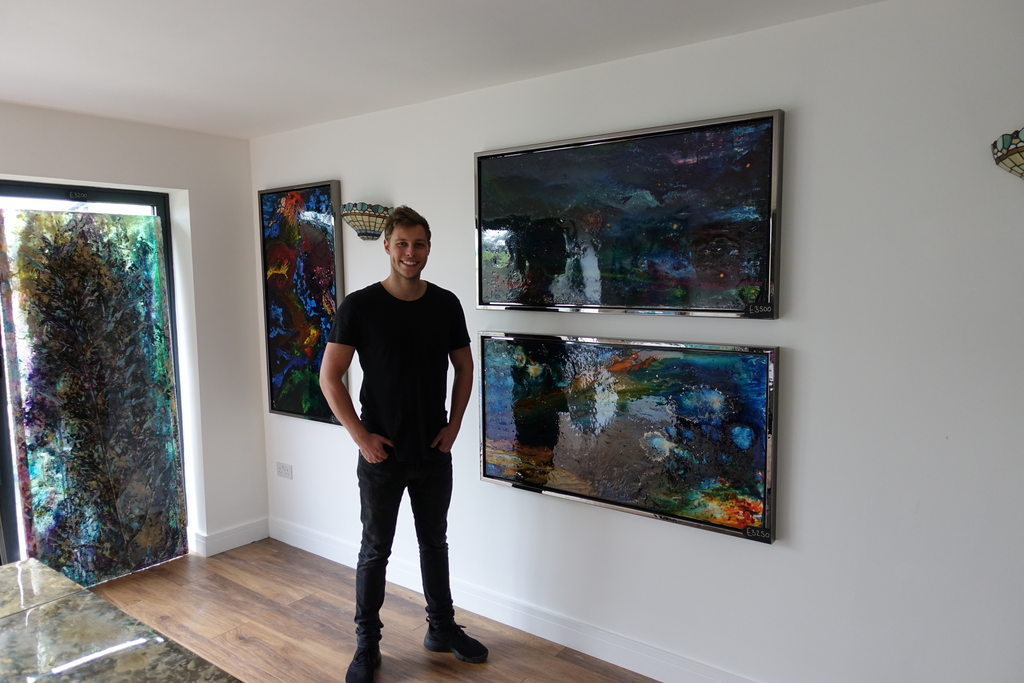 Max standing beside large framed works, showing their scale