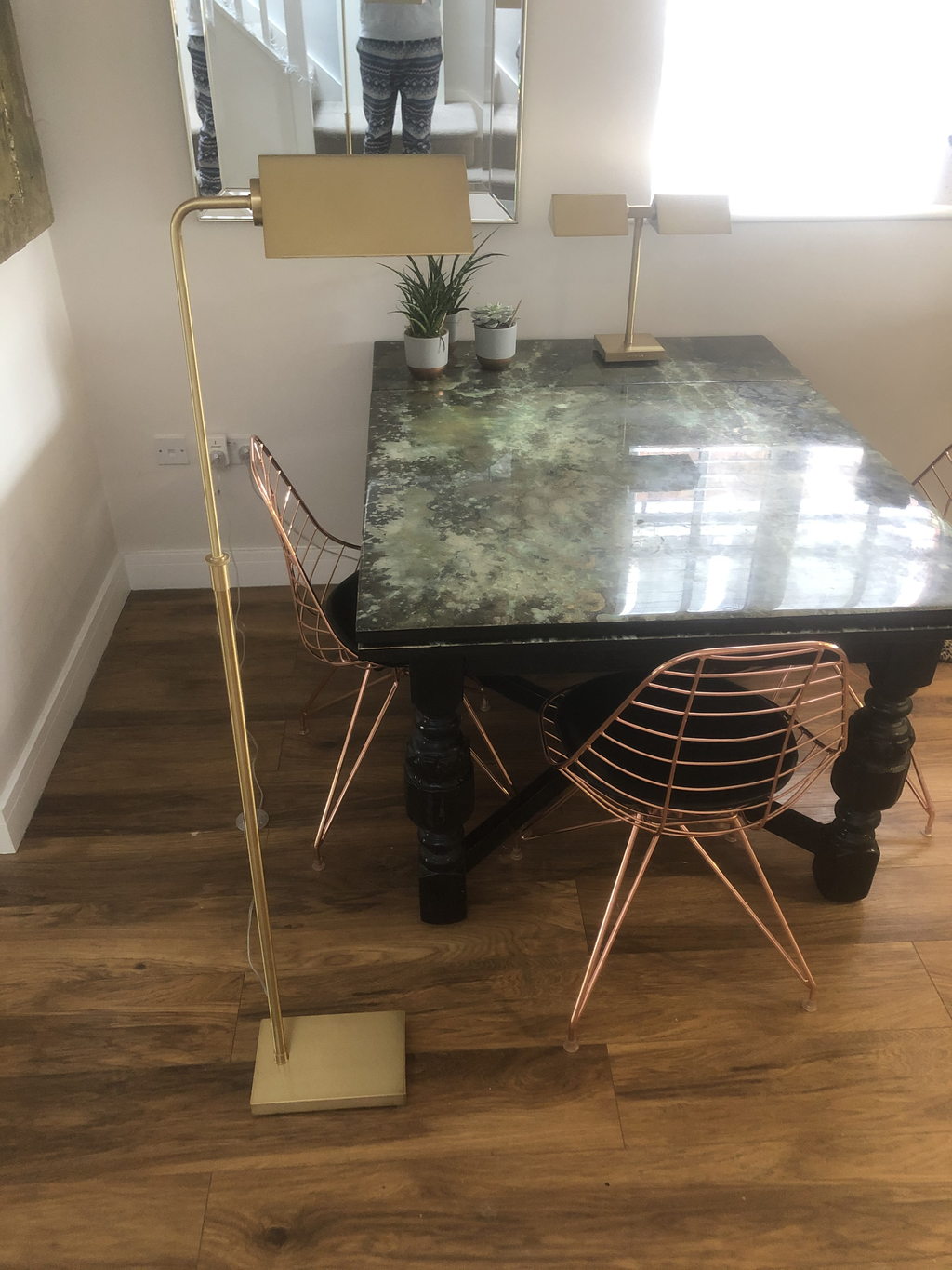 Desk with deep green resin top beside a brass lamp