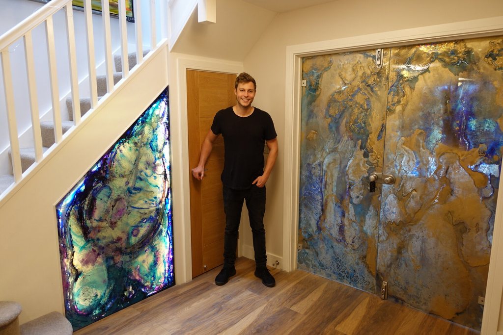 Custom backlit installation fitted under the stairs beside gilded glass doors
